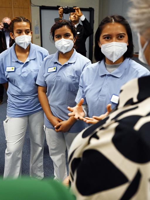 Vier weibliche Auszubildende aus El Salvador stehen Maske tragend nebeneinander und sprechen mit Thüringens Gesundheitsministerin.
