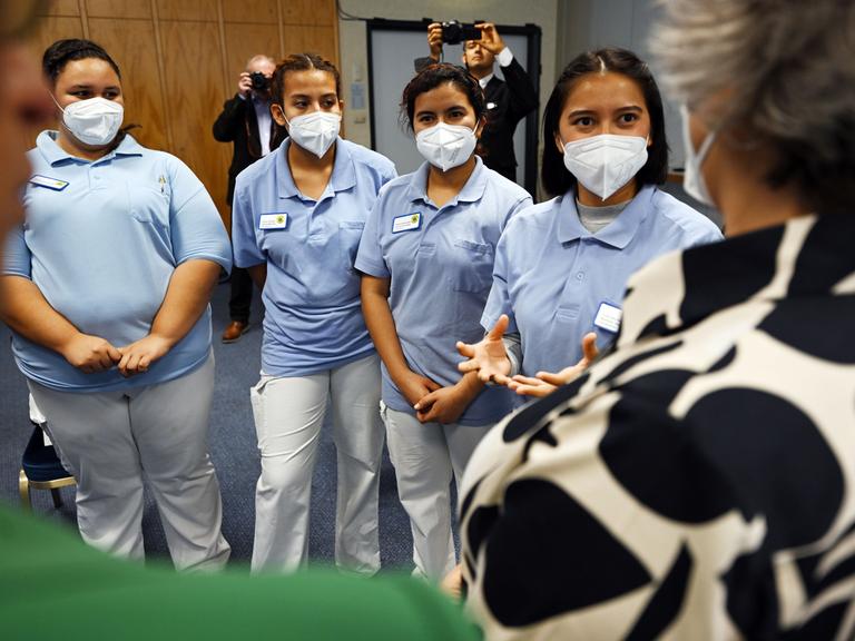 Vier weibliche Auszubildende aus El Salvador stehen Maske tragend nebeneinander und sprechen mit Thüringens Gesundheitsministerin.