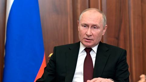 Wladimir Putin sitzt an einem Schreibtisch und spricht in die Kamera