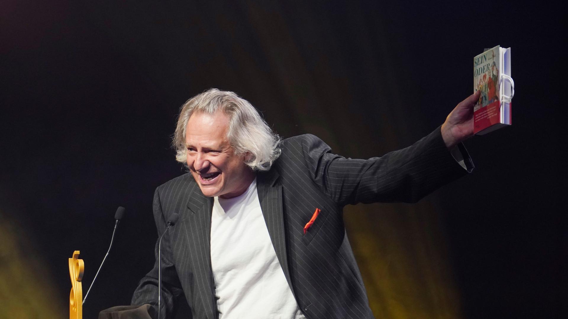 Klaus Pohl auf der Bühne mit Buch bei der Verleihung des deutschen Schauspielpreises 2021 im Spindler und Klatt in Berlin. Klaus Pohl auf der Bühne mit Buch bei der Verleihung des deutschen Schauspielpreises 2021 im Spindler und Klatt in Berlin.