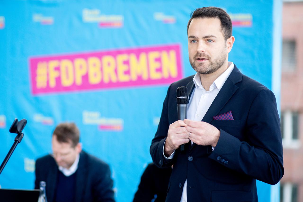 Ein jünger Mann mit kurzen Haaren steht auf einem Podium.