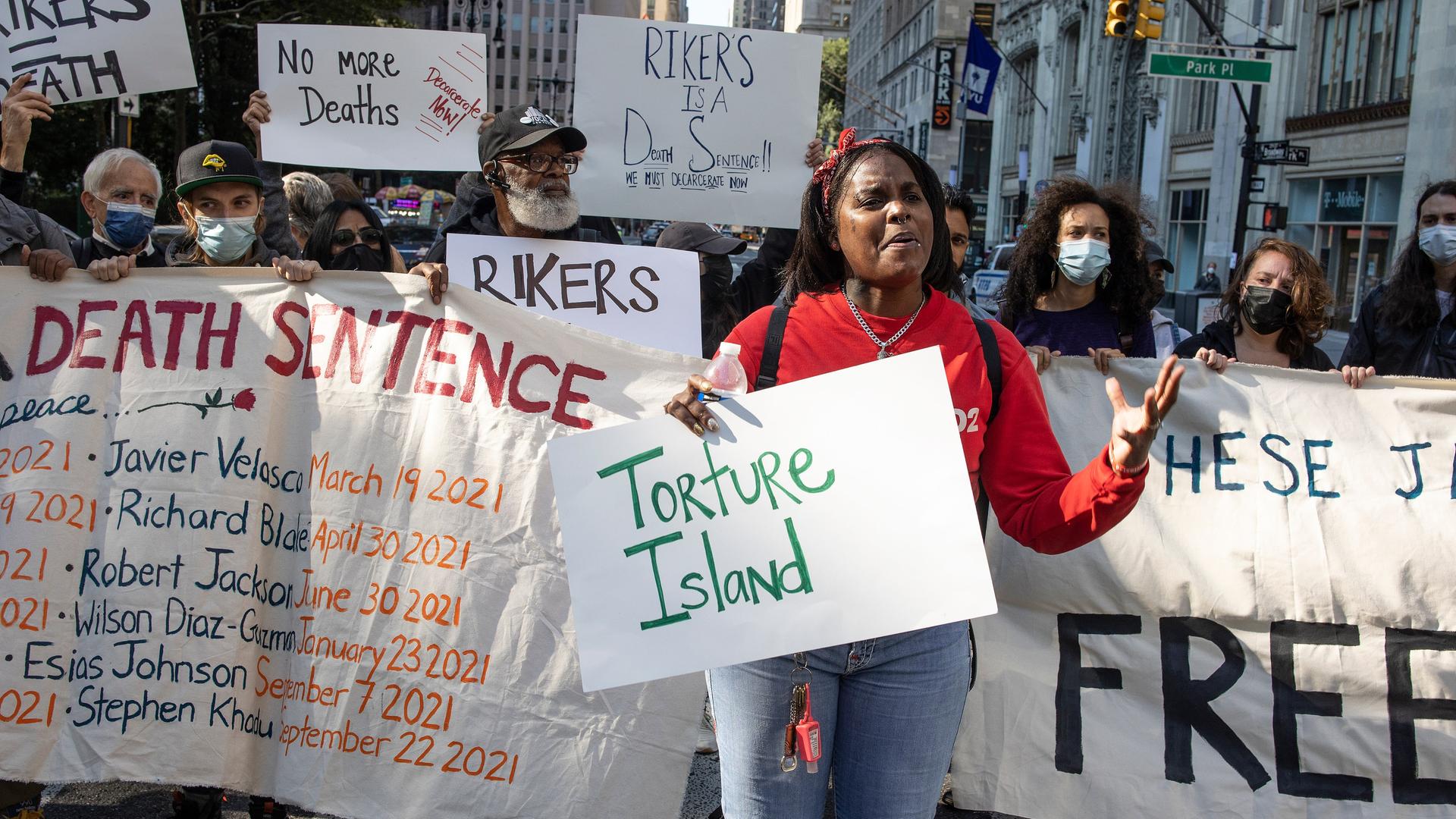 "Torture Island" steht auf einem Schild bei einem Protest in NYC vor der City Hall in Manhattan, weil im Rikers Island Gefängnis Familienangehörige zu Tode kamen.