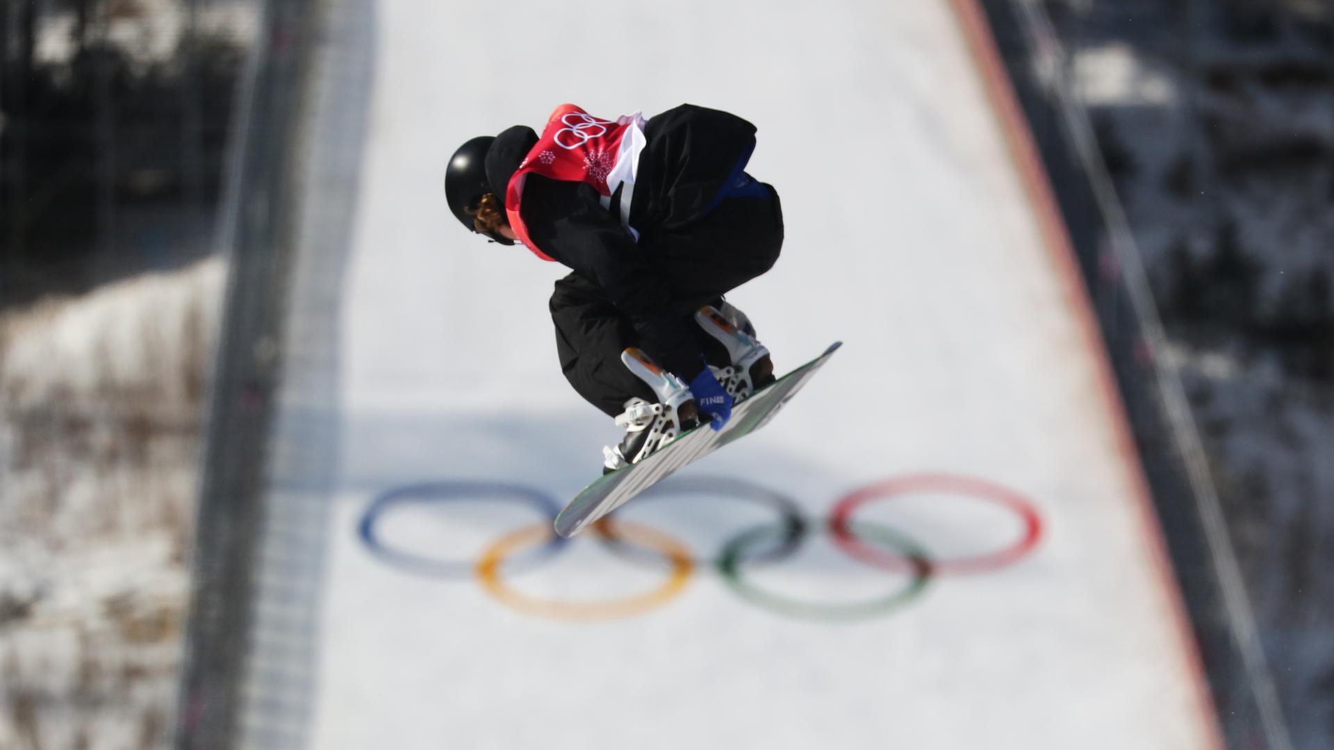 Petr Horak in gebeugter Haltung in der Luft auf seinem Snowboard. Im Hintergrund eine Schanze mit den Olympischen Ringen. Petr Horak in gebeugter Haltung in der Luft auf seinem Snowboard. Im Hintergrund eine Schanze mit den Olympischen Ringen.
