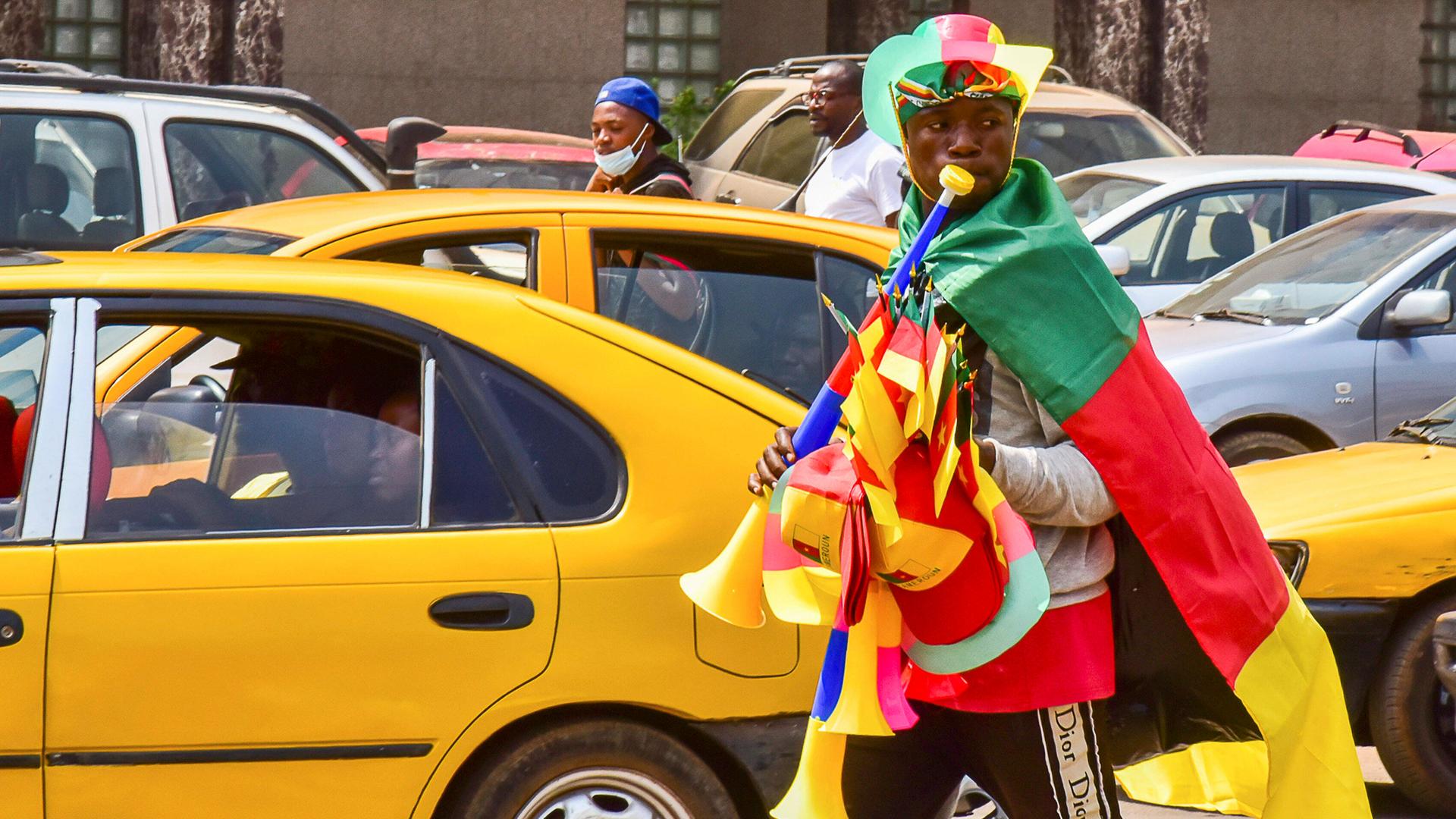 220108 -- YAOUNDE, Jan. 8, 2022 -- Photo taken on Jan. 4, 2022 shows a young man on the street selling gadgets with colors of the Cameroon flag in Yaounde, capital of Cameroon. Africa Cup of Nations AFCON of football, a biennial competition will kick off this Sunday in Yaounde, capital of Cameroon. As an important sport event on the continent, it has attracted the attention of all Cameroonian fans. As a prelude to the opening ceremony, an atmosphere of this competition could already be remarked in the city. Photo by /Xinhua SPCAMEROON-YAOUNDE-FOOTBALL-AFRICA CUP OF NATIONS-UPCOMING Kepseu PUBLICATIONxNOTxINxCHN 220108 -- YAOUNDE, Jan. 8, 2022 -- Photo taken on Jan. 4, 2022 shows a young man on the street selling gadgets with colors of the Cameroon flag in Yaounde, capital of Cameroon. Africa Cup of Nations AFCON of football, a biennial competition will kick off this Sunday in Yaounde, capital of Cameroon. As an important sport event on the continent, it has attracted the attention of all Cameroonian fans. As a prelude to the opening ceremony, an atmosphere of this competition could already be remarked in the city. Photo by /Xinhua SPCAMEROON-YAOUNDE-FOOTBALL-AFRICA CUP OF NATIONS-UPCOMING Kepseu PUBLICATIONxNOTxINxCHN