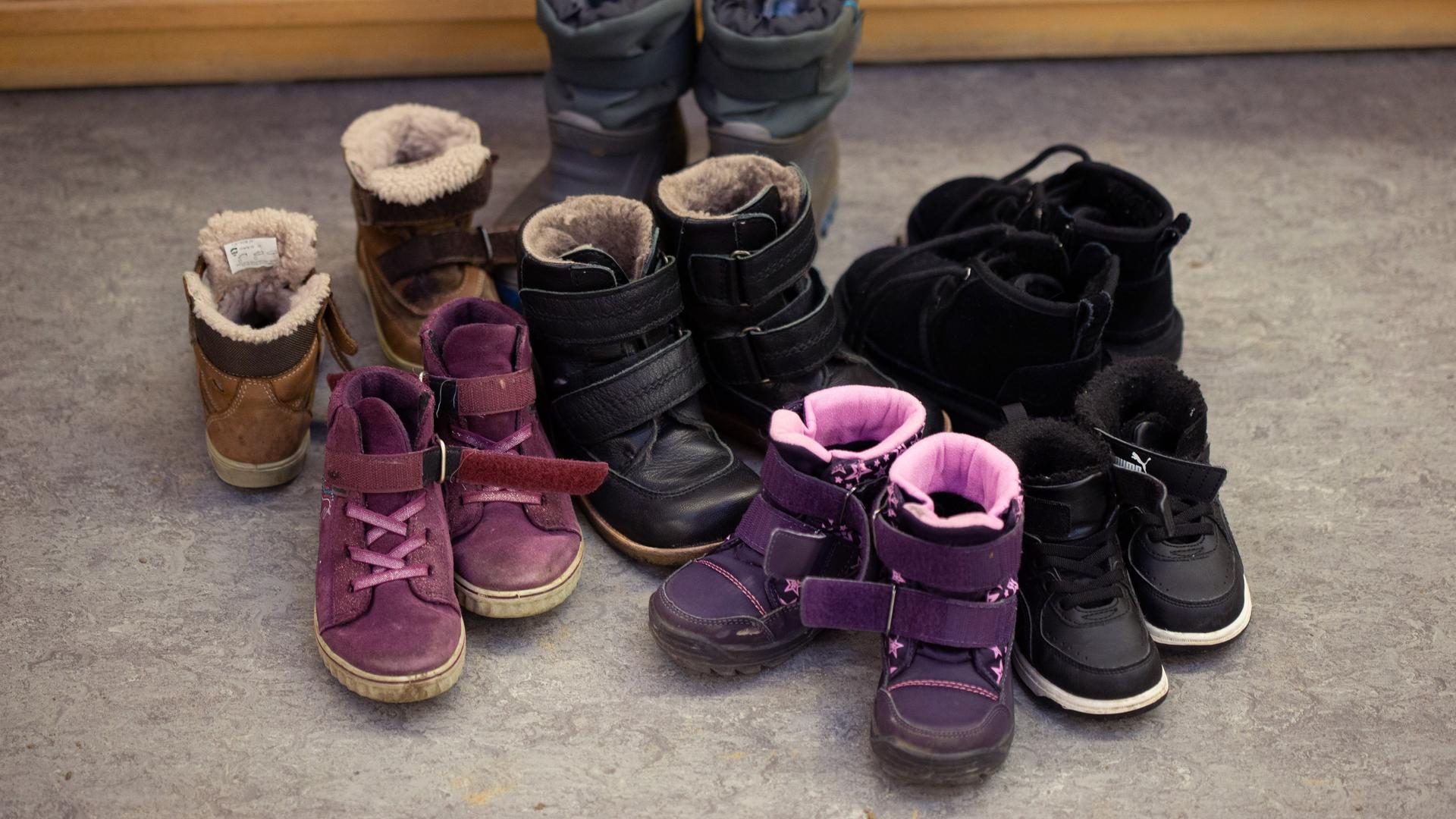 Kinderschuhe und Kinderstiefel sind auf dem Boden in einer Kindertagesstätte abgestellt. Kinderschuhe und Kinderstiefel sind auf dem Boden in einer Kindertagesstätte abgestellt.