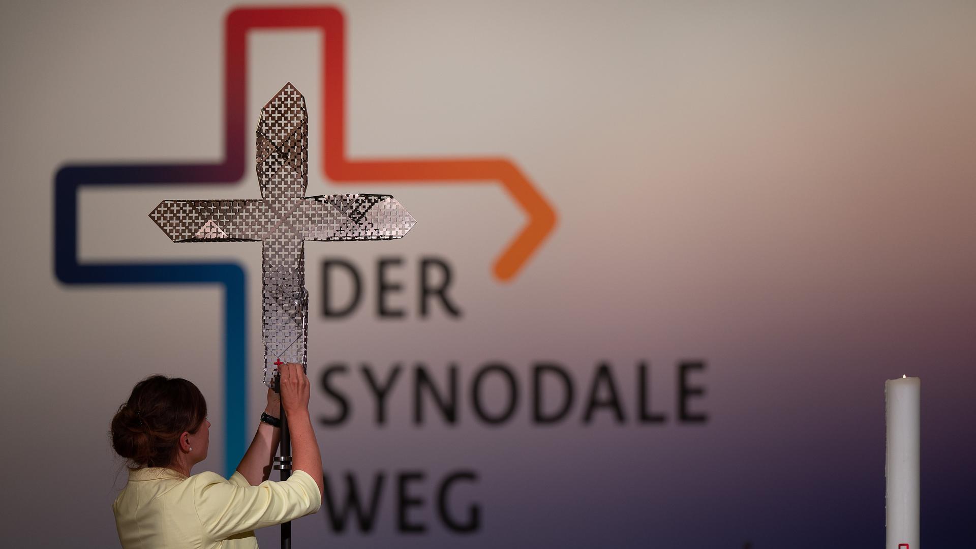 Eine Frau steckt während der vierten Synodalversammlung der katholischen Kirche in Deutschland im Congress Center Messe Frankfurt dem Synodalkreuz ein rotes kleines Kreuz an. Eine Frau steckt während der vierten Synodalversammlung der katholischen Kirche in Deutschland im Congress Center Messe Frankfurt dem Synodalkreuz ein rotes kleines Kreuz an.