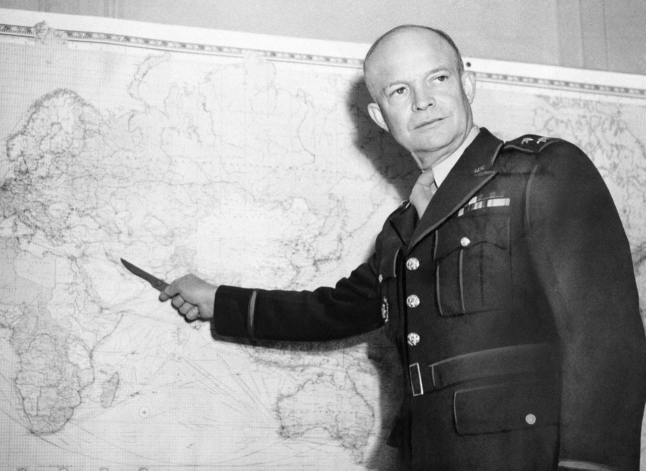 Für einen Besucher seines Londoner Hauptquartiers veranschaulicht Generalleutnant Dwight D. Eisenhower, der die Streitkräfte der US-Armee im Europäischen Kriegsschauplatz befehligt, etwas auf einer an der Wand hängenden Karte.