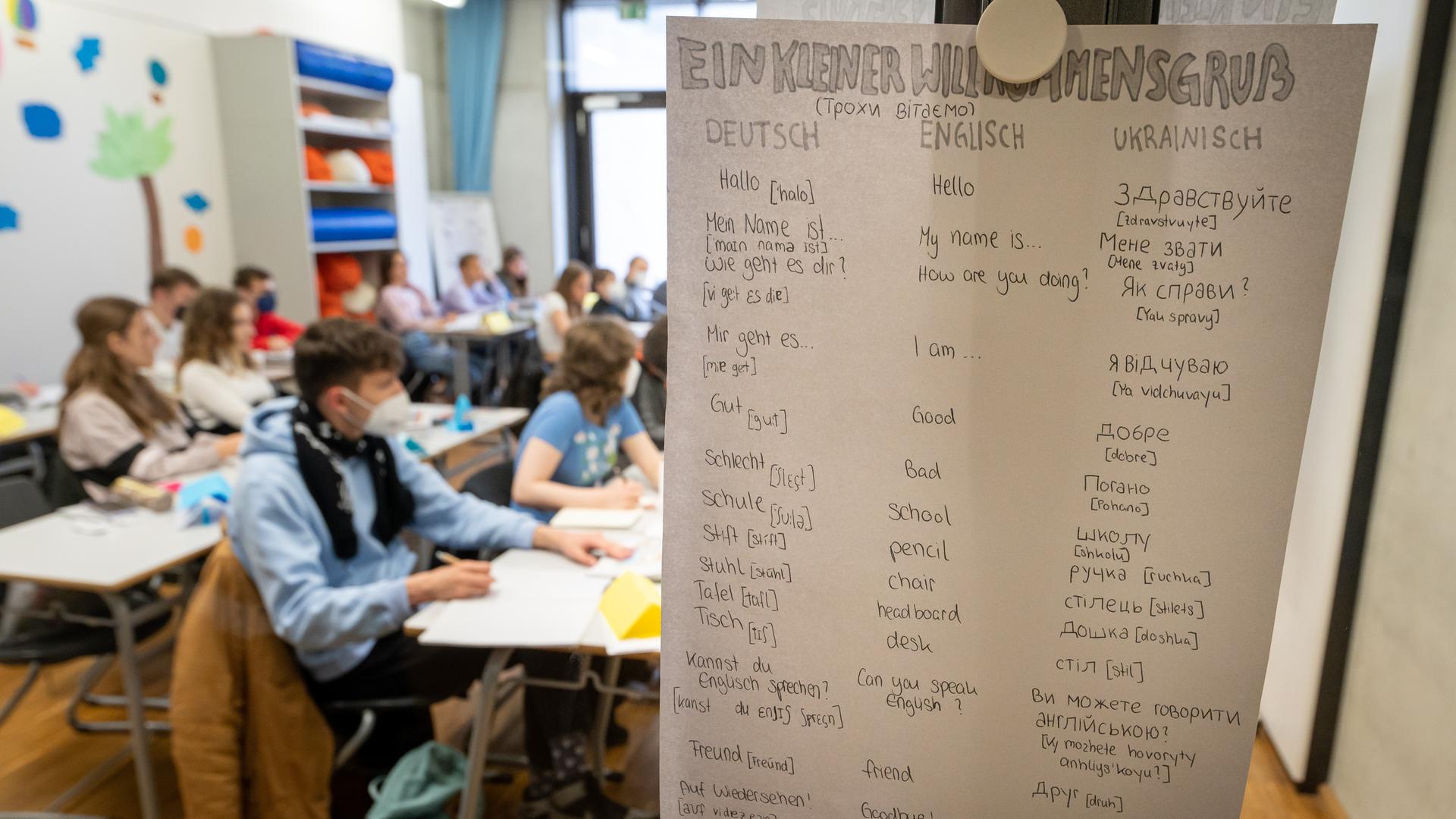 Kinder aus der Ukraine sitzen am Morgen in einer Willkommensklasse des Gymnasium Trudering. An einem Pfahl hängt ein Zettel mit einem Willkommensgruà auf Deutsch, Englisch und Ukrainisch. Kinder aus der Ukraine sitzen am Morgen in einer Willkommensklasse des Gymnasium Trudering. An einem Pfahl hängt ein Zettel mit einem Willkommensgruà auf Deutsch, Englisch und Ukrainisch.