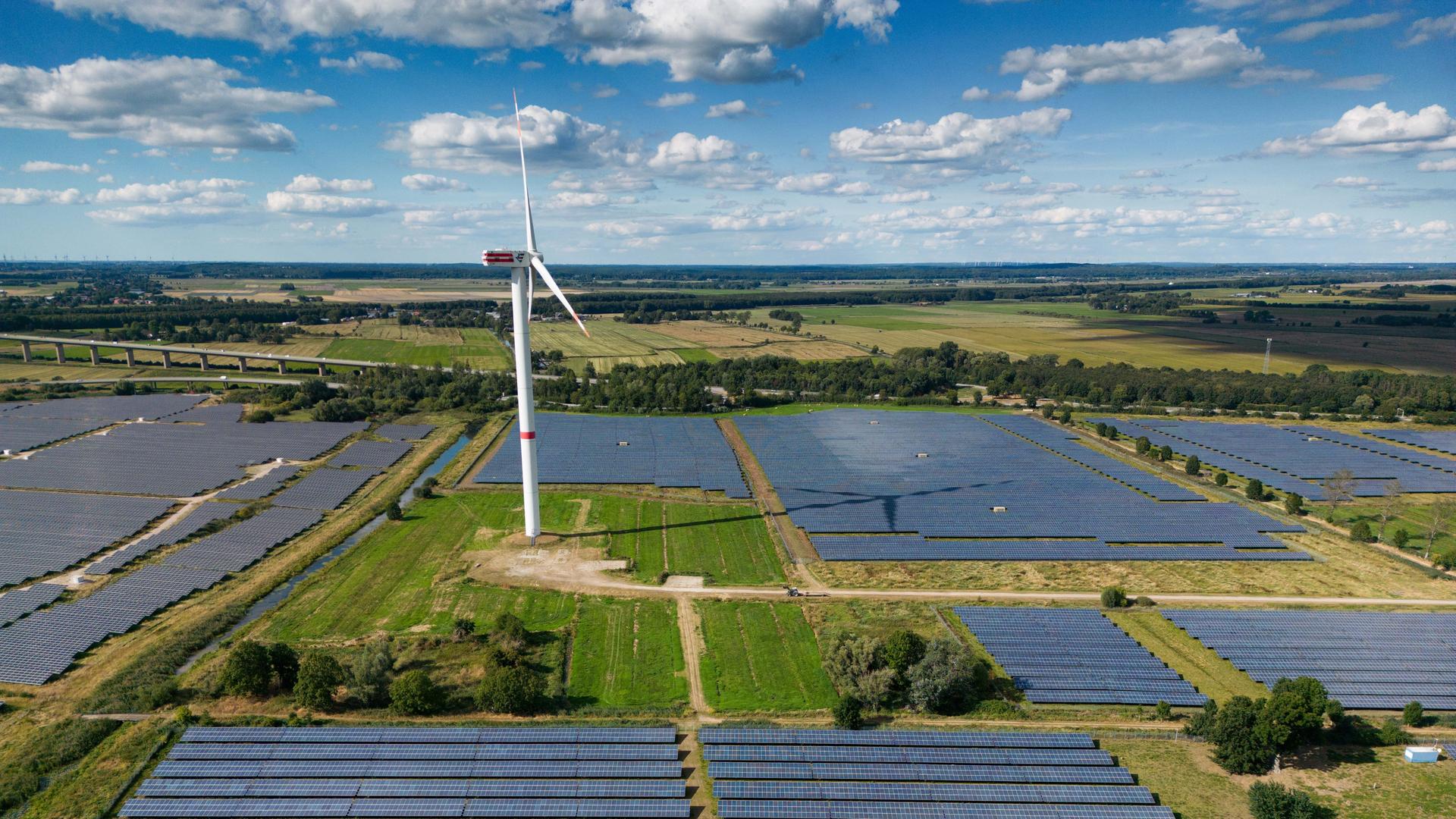 Eine Photovoltaik-Freiflächenanlage (Solarpark), betrieben von der Firma Enerparc. Zahlreiche Solarzellen in dem Solarkraftwerk wandeln Sonnenenergie in grünen Strom um. In dem Solarpark steht ein Windrad. (Luftaufnahme mit Drohne) Eine Photovoltaik-Freiflächenanlage (Solarpark), betrieben von der Firma Enerparc. Zahlreiche Solarzellen in dem Solarkraftwerk wandeln Sonnenenergie in grünen Strom um. In dem Solarpark steht ein Windrad. (Luftaufnahme mit Drohne)