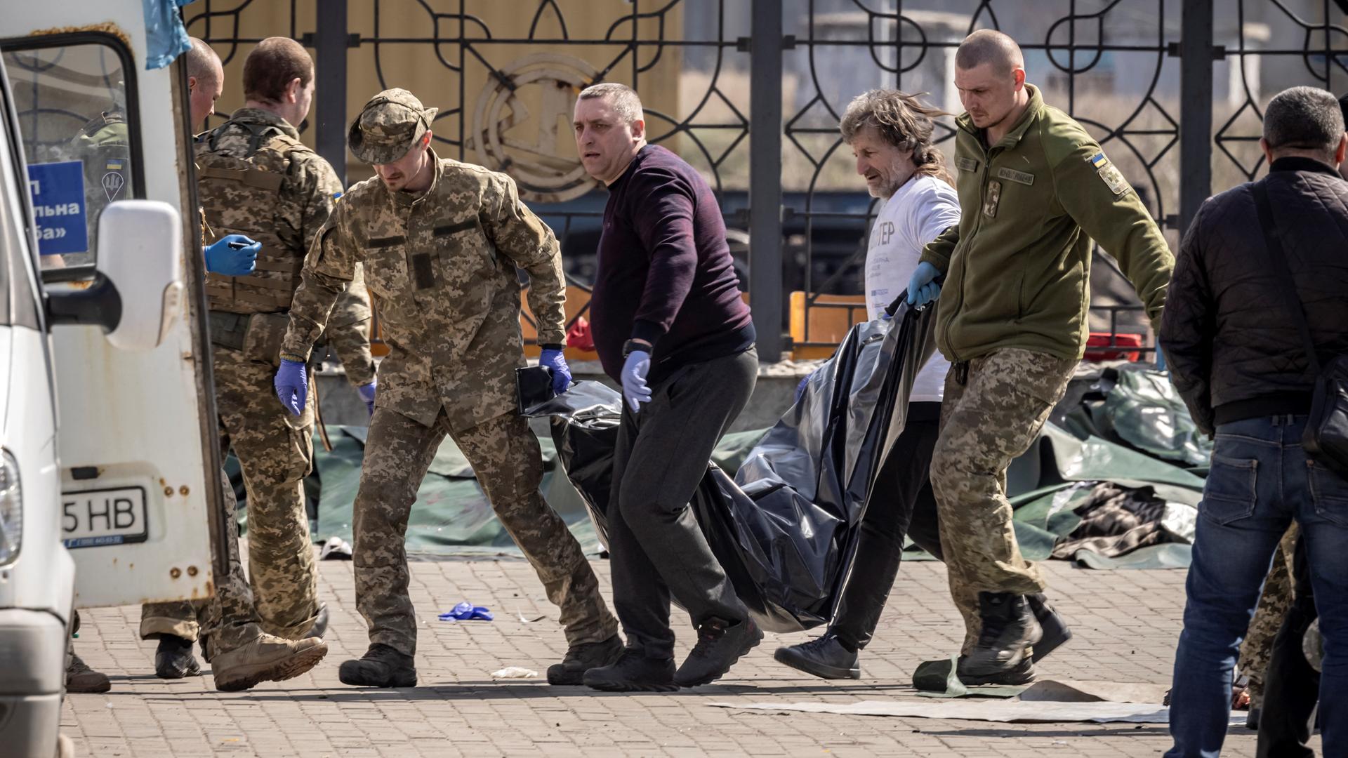 Ukrainische Soldaten und Helfer tragen eine Leiche nach dem Anschlag auf den Bahnhof in Kramatorsk weg.