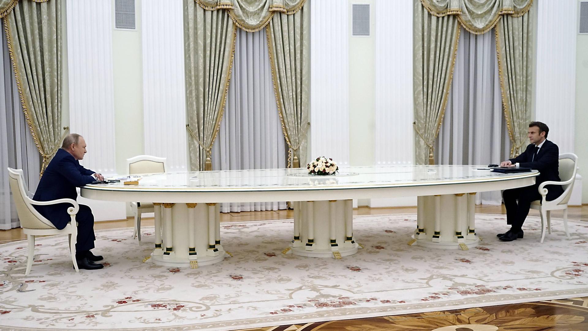 Putin und Macron sitzen an einem sehr langen Tisch in Moskau. Putin und Macron sitzen an einem sehr langen Tisch in Moskau.