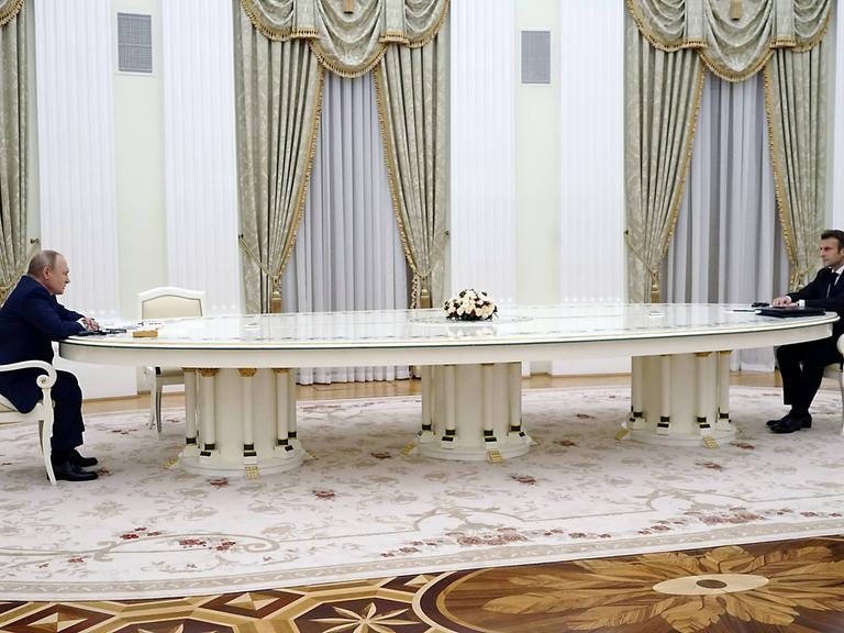 Putin und Macron sitzen an einem sehr langen Tisch in Moskau.