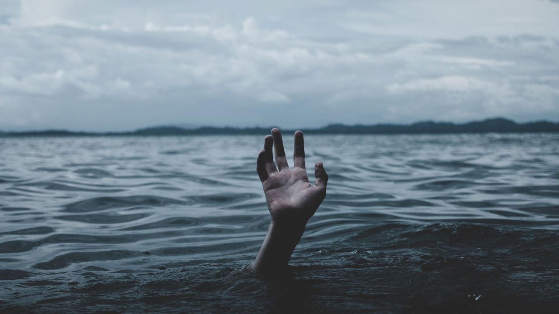 Eine Hand schaut aus dem Meer heraus.