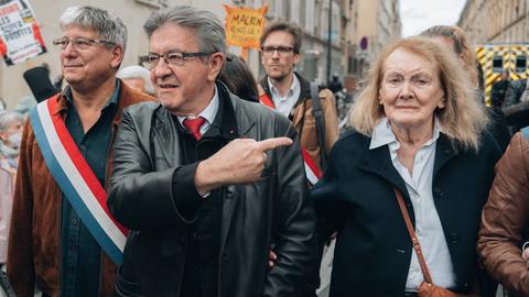 Literaturnobelpreisträgerin Annie Ernaux demonstriert in Paris mit vielen anderen Menschen. Links von ihr der Linkspopulist Jean-Luc Mélenchon, der auf sie zeigt.