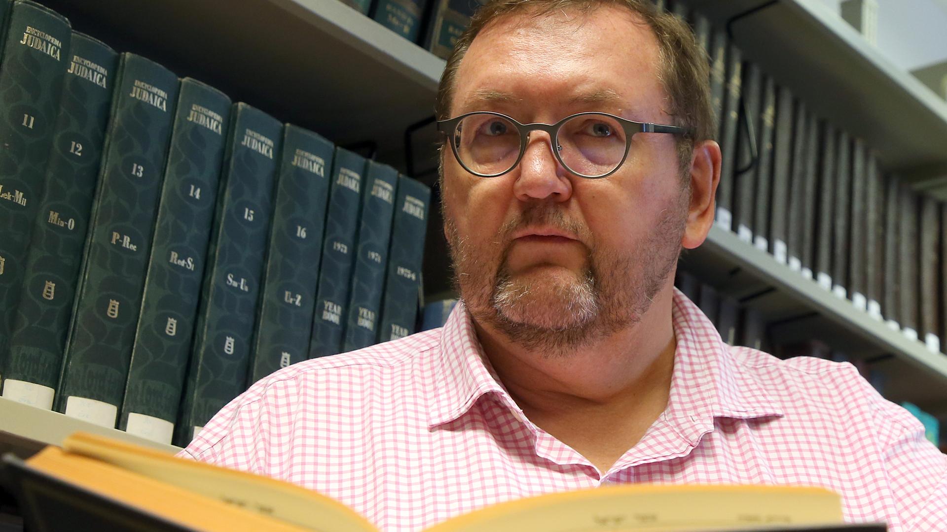 Walter Homolka mit einem Buch in der Hand, vor einem Buchregal Walter Homolka mit einem Buch in der Hand, vor einem Buchregal