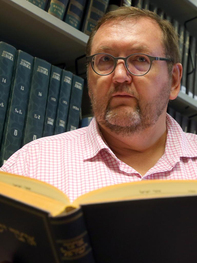 Walter Homolka mit einem Buch in der Hand, vor einem Buchregal