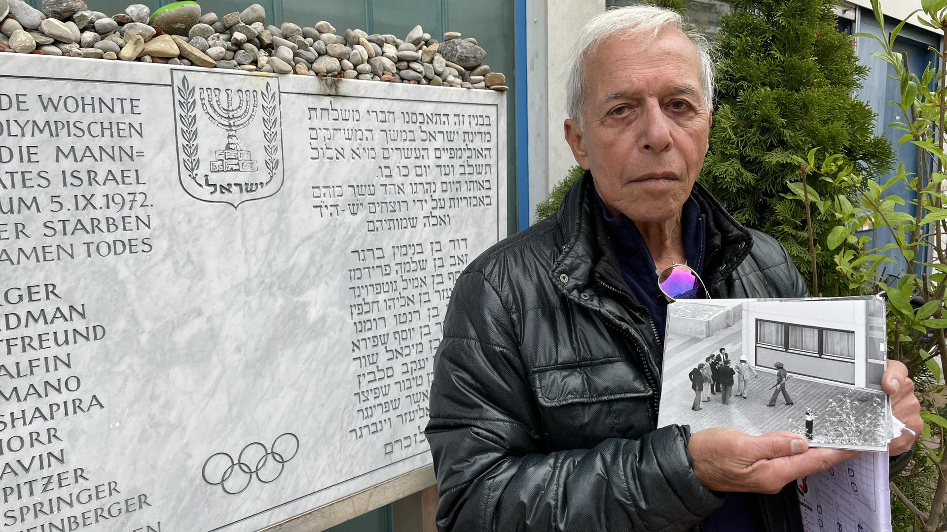 Shlomo Levy posiert mit einem historischen Foto neben der Gedenktafel im Olympischen Dorf in München für ein Foto. Shlomo Levy posiert mit einem historischen Foto neben der Gedenktafel im Olympischen Dorf in München für ein Foto.
