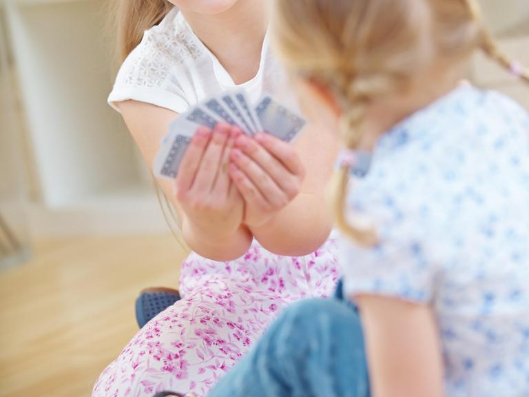 Zwei junge Mädchen spielen gemeinsam mit Karten.