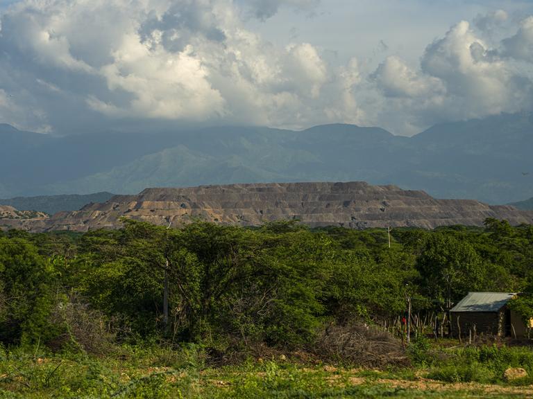 Blick auf ein Waldgebiet in der Nähe des Rancheria-Flusses, in dessen Umgebung das indigene Volk der Wayú lebt. Im Hintergrund türmt sich die Cerrejón-Kohlemine.