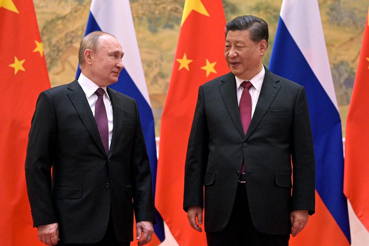 Wladimir Putin und Xi Jinping posieren vor russischen und chinesischen Flaggen und schauen einander an.