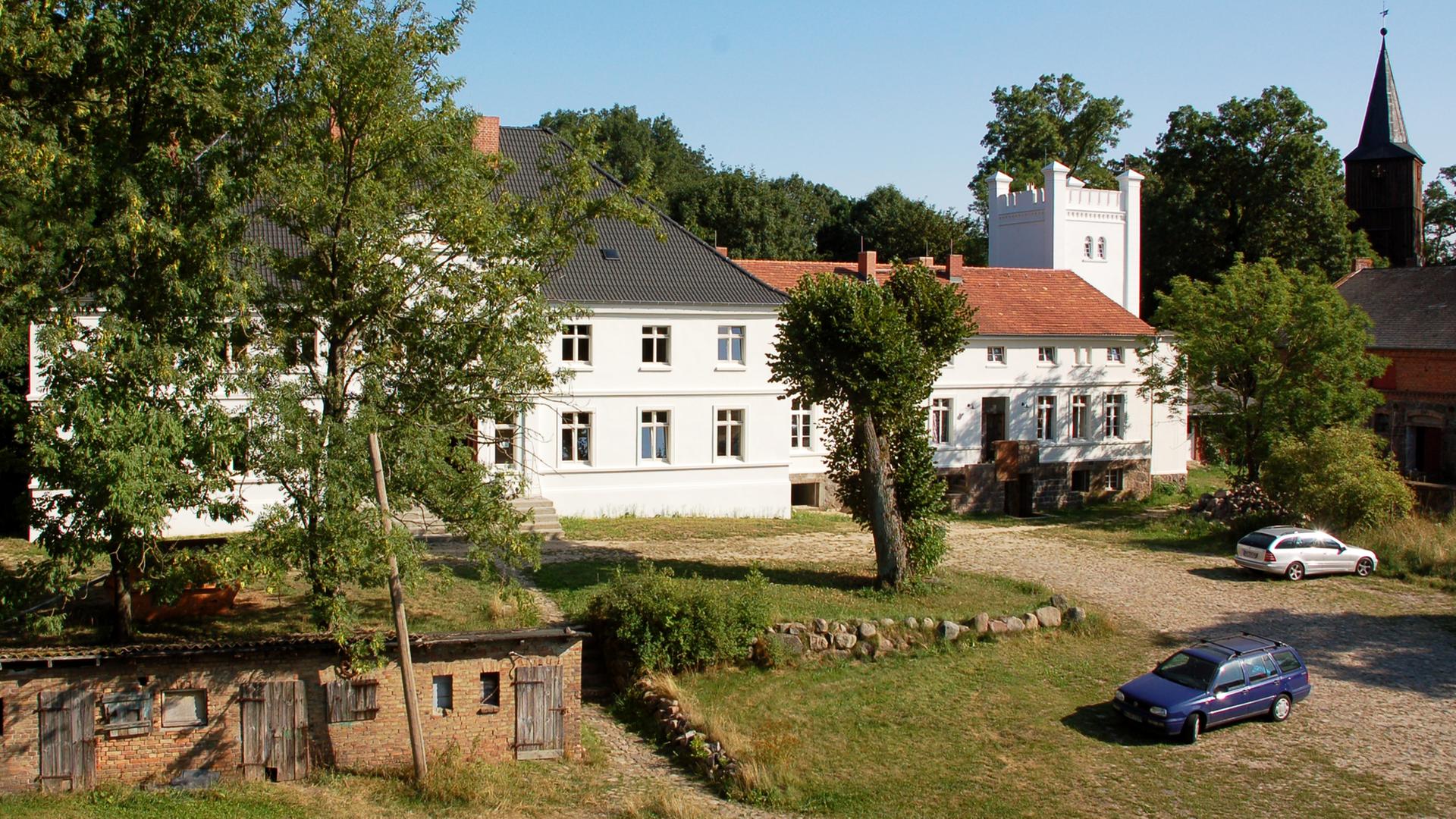 Aufnahme von Schloss Bröllin, im Vordergrund stehen links einige Bäume, das Gebäude mitsamt des mächtigen Turmes an der rechten Seite ist weiß angemalert. Im Hintergrund des Schlosses sind Baumkronen zu erkennen. Aufnahme von Schloss Bröllin, im Vordergrund stehen links einige Bäume, das Gebäude mitsamt des mächtigen Turmes an der rechten Seite ist weiß angemalert. Im Hintergrund des Schlosses sind Baumkronen zu erkennen.