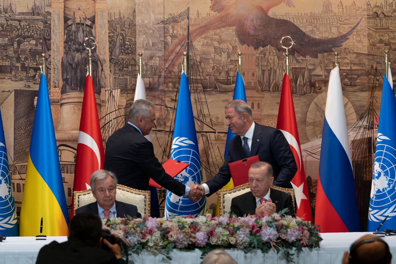 Zwei Abgesandte von Russland und der Ukraine schütteln sich die Hände, im Vordergrund sitzen der türkische Präsident Erdogan und UNO-Generalsekreätr Guterres. Zwei Abgesandte von Russland und der Ukraine schütteln sich die Hände, im Vordergrund sitzen der türkische Präsident Erdogan und UNO-Generalsekreätr Guterres.
