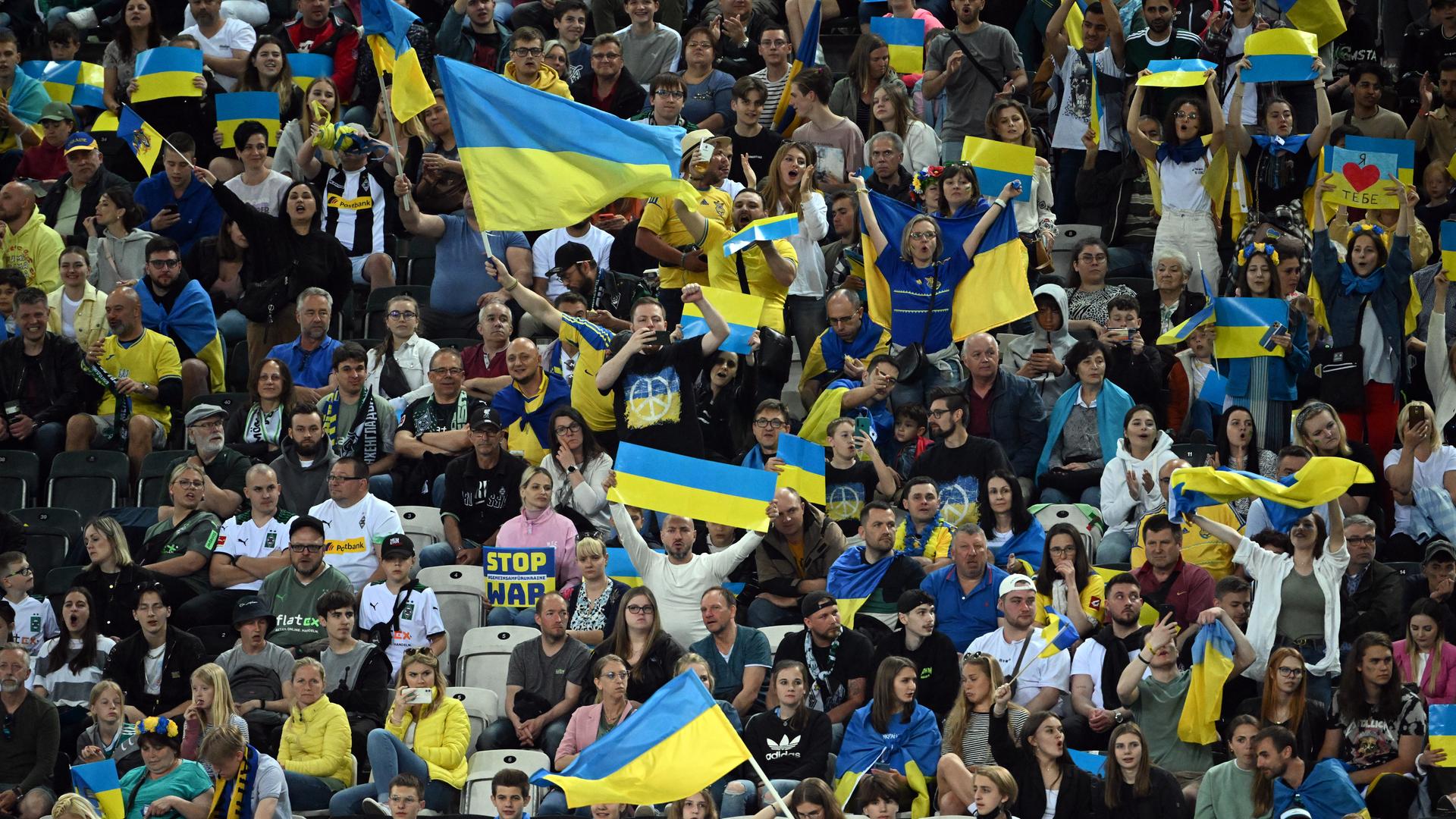 Menschen im Stadion schwenken ukraninische Flaggen. Menschen im Stadion schwenken ukraninische Flaggen.