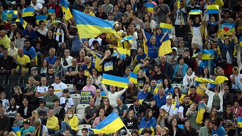 Menschen im Stadion schwenken ukrainische Flaggen.