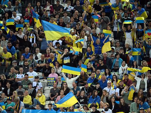 Menschen im Stadion schwenken ukraninische Flaggen.