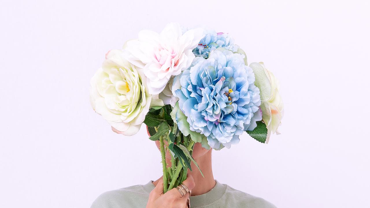 Eine Person verdeckt das Gesicht mit einem Blumenstrauß Eine Person verdeckt das Gesicht mit einem Blumenstrauß