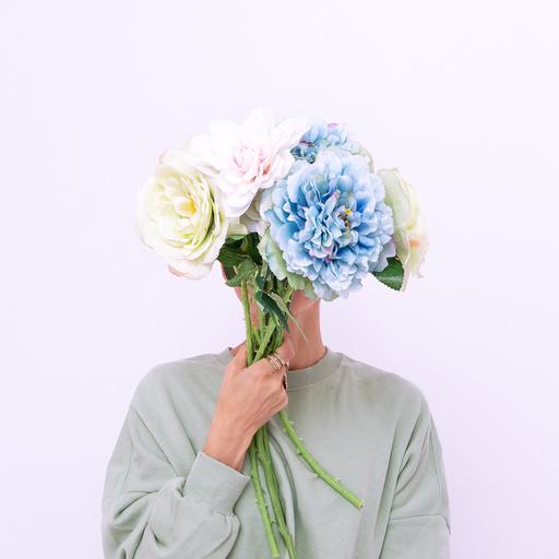 Eine Person verdeckt das Gesicht mit einem Blumenstrauß