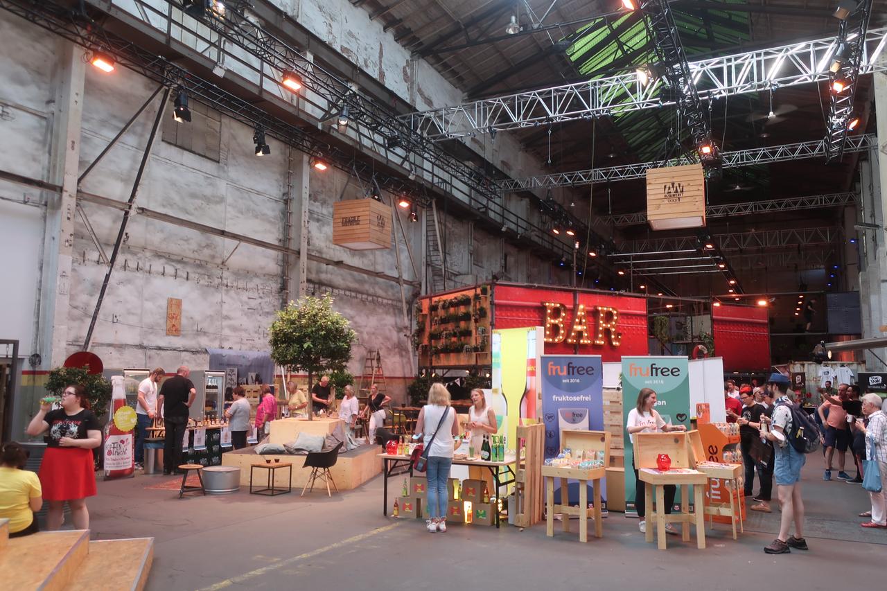 In einer großen Halle sind verschiedene Stände mit Lebensmitteln zum Probieren aufgebaut. In einer großen Halle sind verschiedene Stände mit Lebensmitteln zum Probieren aufgebaut.