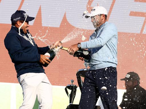 Profigolfer Charl Schwartzel und Hennie Du Plessis feiern bei der Siegerehrung der LIV Golf Invitational Series. 