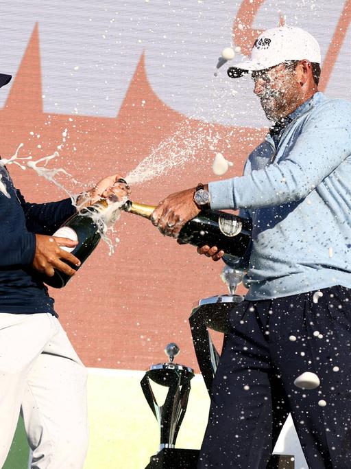 Profigolfer Charl Schwartzel und Hennie Du Plessis feiern bei der Siegerehrung der LIV Golf Invitational Series. 