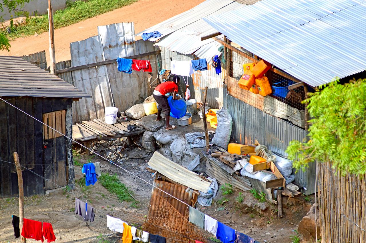 Blick in ein Wellblechgehöft in der südsudanesischen Hauptstadt Juba. Ein junger Mann reinigt eine Plastikwanne. Blick in ein Wellblechgehöft in der südsudanesischen Hauptstadt Juba. Ein junger Mann reinigt eine Plastikwanne.