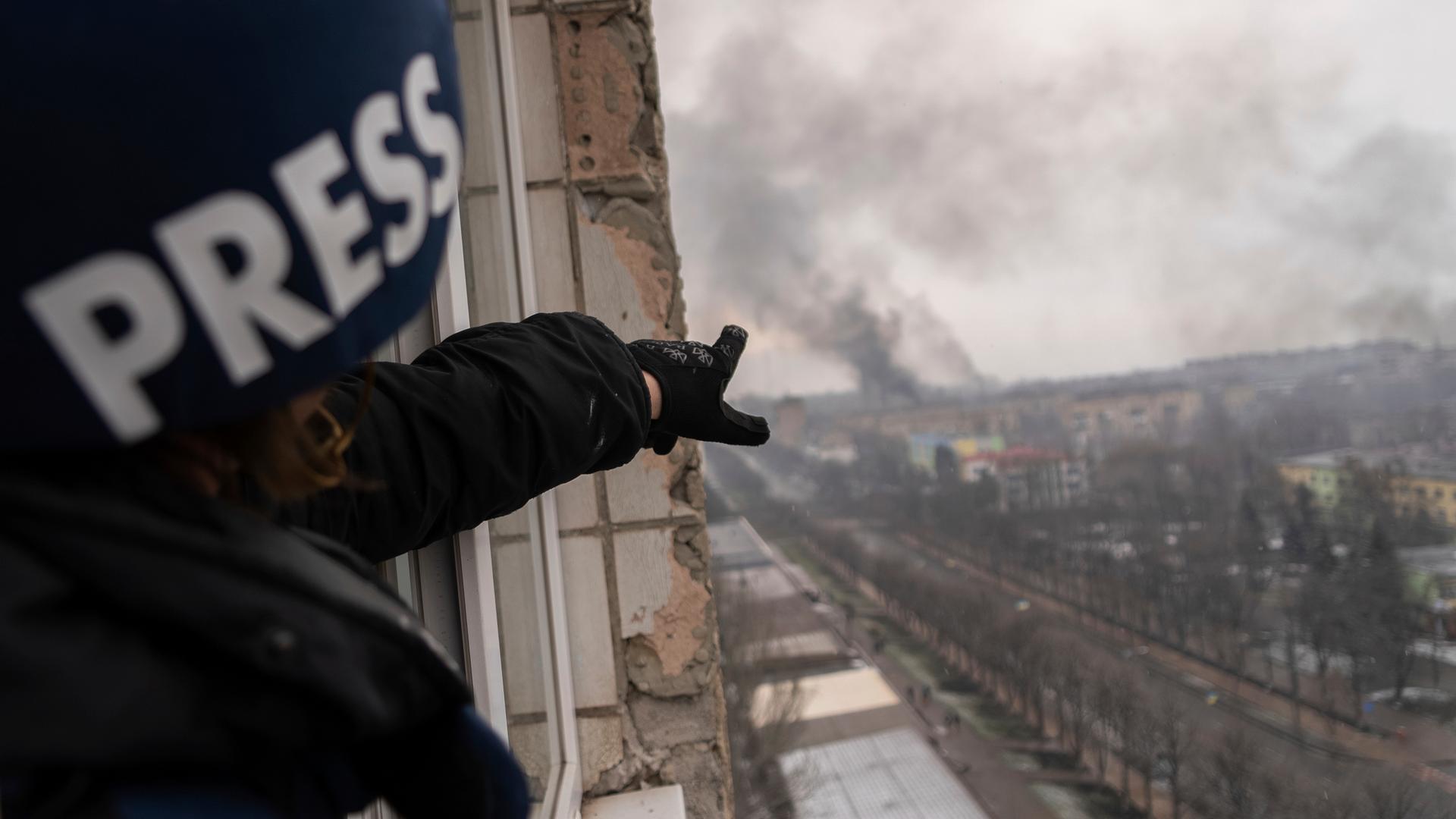 Das englische Wort "Press" für Presse steht auf dem Helm einer Fotografin, die auf Rauch über der ukrainischen Stadt Mariupol zeigt. Das englische Wort "Press" für Presse steht auf dem Helm einer Fotografin, die auf Rauch über der ukrainischen Stadt Mariupol zeigt.