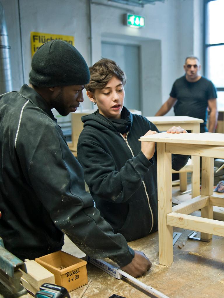 Flüchtlinge aus Afrika und dem Balkan arbeiten in einer Holzwerkstatt.
