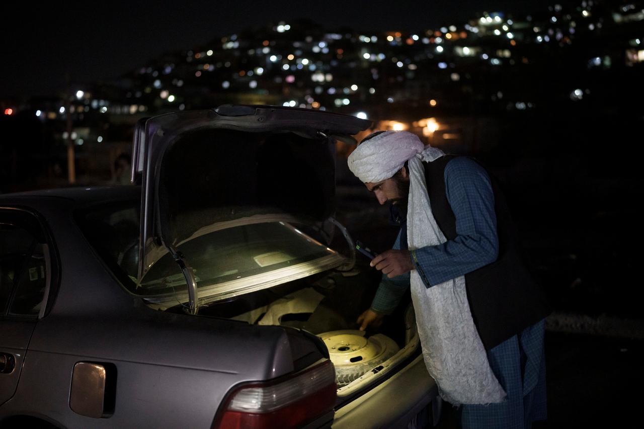 Ein Taliban-Kämpfer durchsucht den Kofferraum eines Autos an einem Checkpoint in Kabul