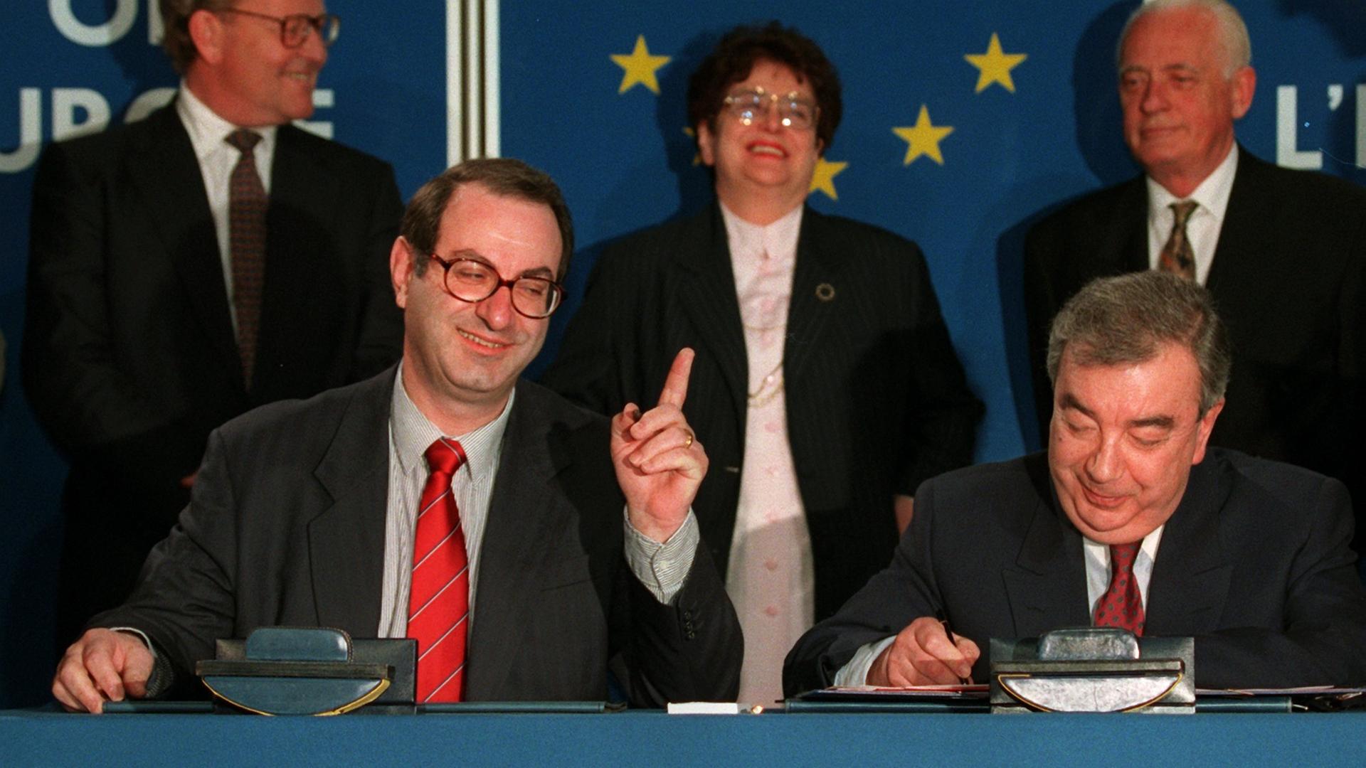 Der Generalsekretär des Europarats, Daniel Tarschys (links im Bild) gestikuliert, während der russische Außenminister, Jewgeni Primakow, am 28. Februar 1996 in Straßburg das Dokument über die Aufnahme Russlands unterzeichnet.