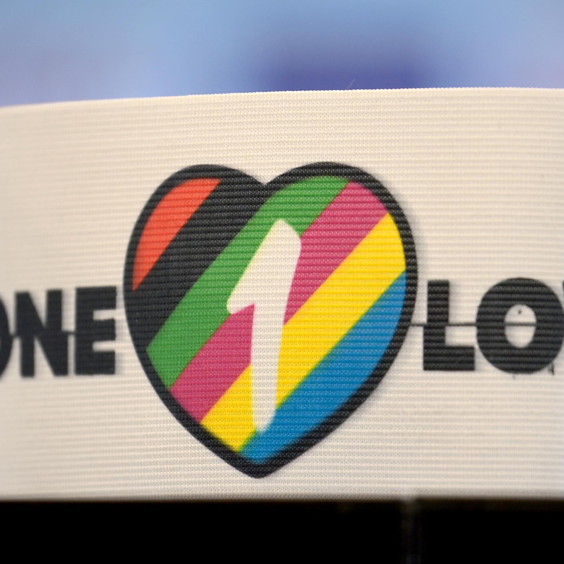 Die spezielle Kapitänsbinde als Zeichen gegen Diskriminierung und für Vielfalt liegt auf einem Tisch. Diese ziert ein Herz in bunten Farben, die für Vielfalt stehen, sowie die Aufschrift 'One Love'.
