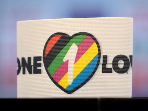Die spezielle Kapitänsbinde als Zeichen gegen Diskriminierung und für Vielfalt liegt auf einem Tisch. Diese ziert ein Herz in bunten Farben, die für Vielfalt stehen, sowie die Aufschrift 'One Love'.