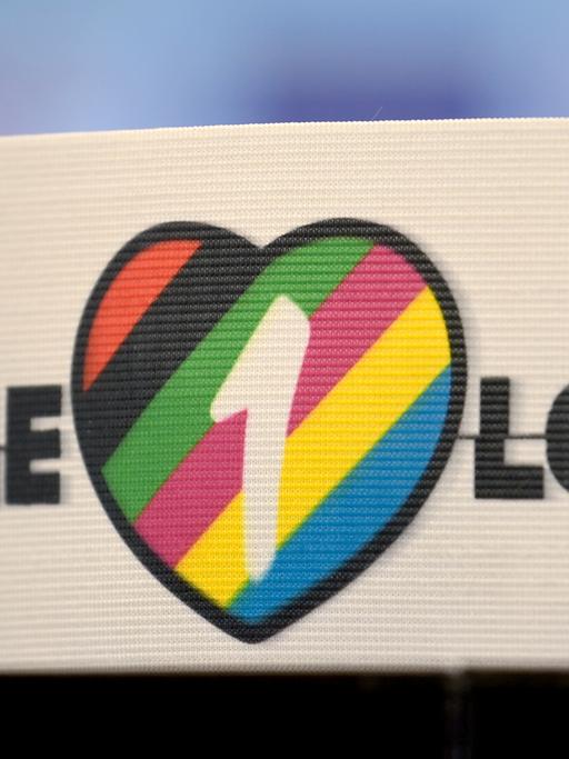 Die spezielle Kapitänsbinde als Zeichen gegen Diskriminierung und für Vielfalt liegt auf einem Tisch. Diese ziert ein Herz in bunten Farben, die für Vielfalt stehen, sowie die Aufschrift 'One Love'.