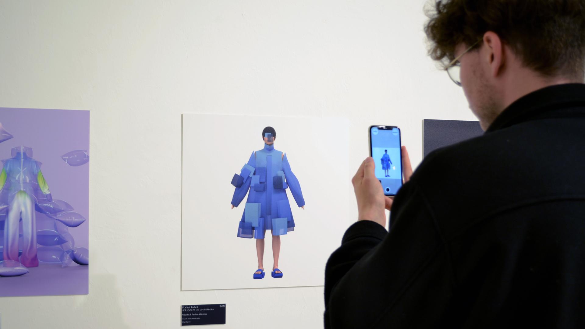 Ein Besucher der Ausstellung "virtuelles Beiwerk" steht mit dem Smartphone vor einem Ausstellungsstück. Ein Besucher der Ausstellung "virtuelles Beiwerk" steht mit dem Smartphone vor einem Ausstellungsstück.