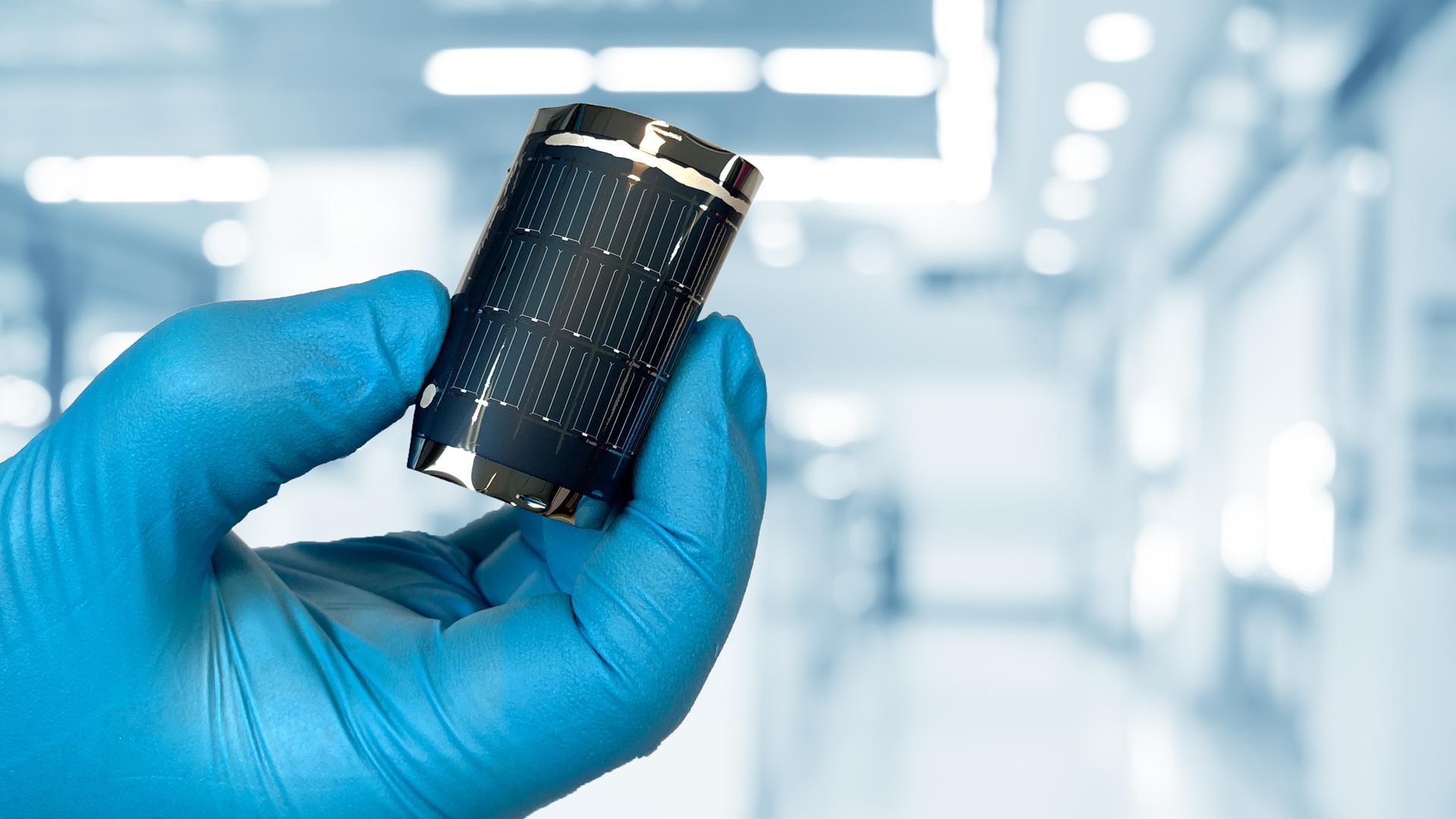 Eine Hand mit blauem Hanschuh biegt eine flexible Solarzelle der Empa Eine Hand mit blauem Hanschuh biegt eine flexible Solarzelle der Empa