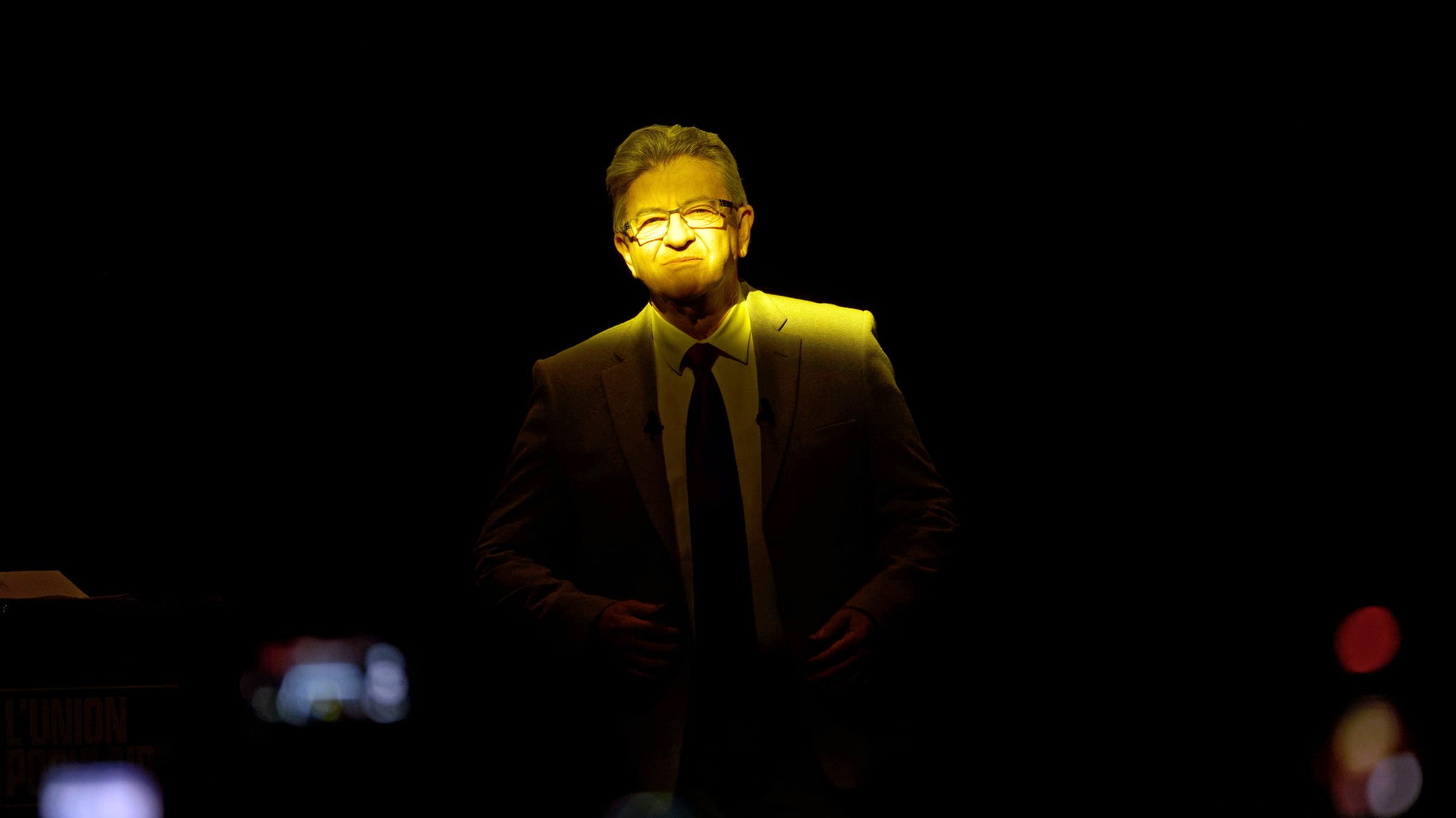 Der französische Präsidentschaftskandidat Jean-Luc Mélenchon bei einer der letzten Wahlkampfveranstaltungen im gelben Licht eines Fensters.