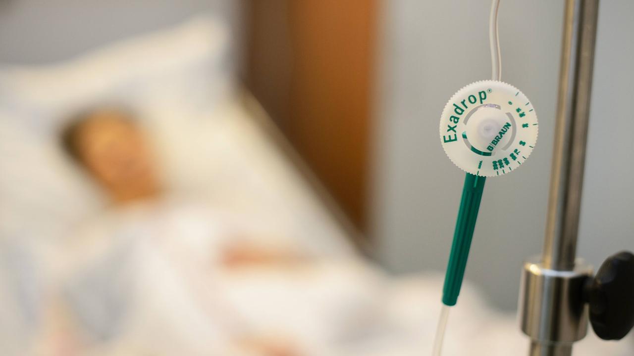 Drehrad zur Regulierung der Geschwindigkeit einer Infusion, unscharf im Hintergrund Patient im Bett (Symbolbild) Drehrad zur Regulierung der Geschwindigkeit einer Infusion, unscharf im Hintergrund Patient im Bett (Symbolbild)
