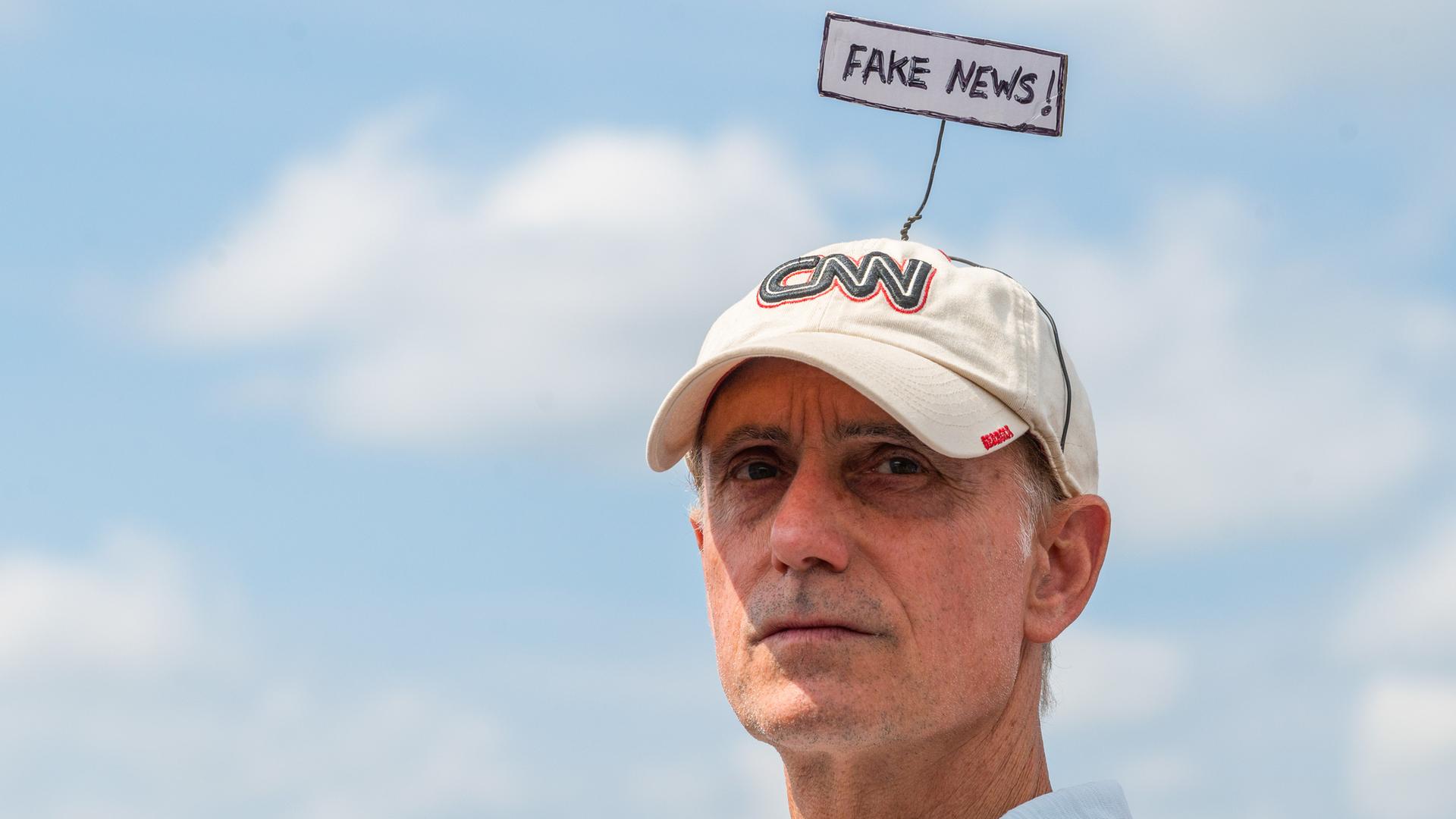 Ein Mann bei der Trump Rally im Wilkes-Barre Township in Pennsylvania mit CNN-Mütze, auf der er ein Schild mit der Aufschrift "Fake News!" befestigt hat, aufgenommen am 03.09.2022
