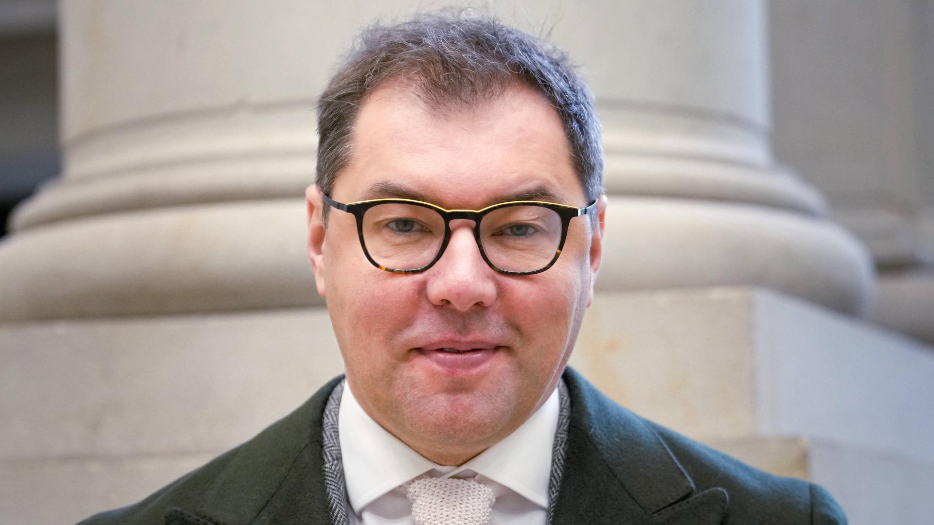 Porträt von Oleksii Makeiev dem Botschafter der Ukraine in Berlin. Er trägt Anzug, einen Mantel und eine Brille und guckt geradeaus in die Kamera.