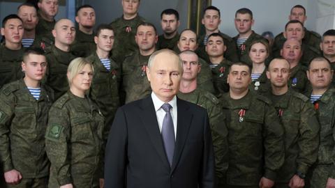 Der russische Präsident Wladimir Putin steht an Neujahr vor Mitgliedern der Armee und posiert für die Kameras
