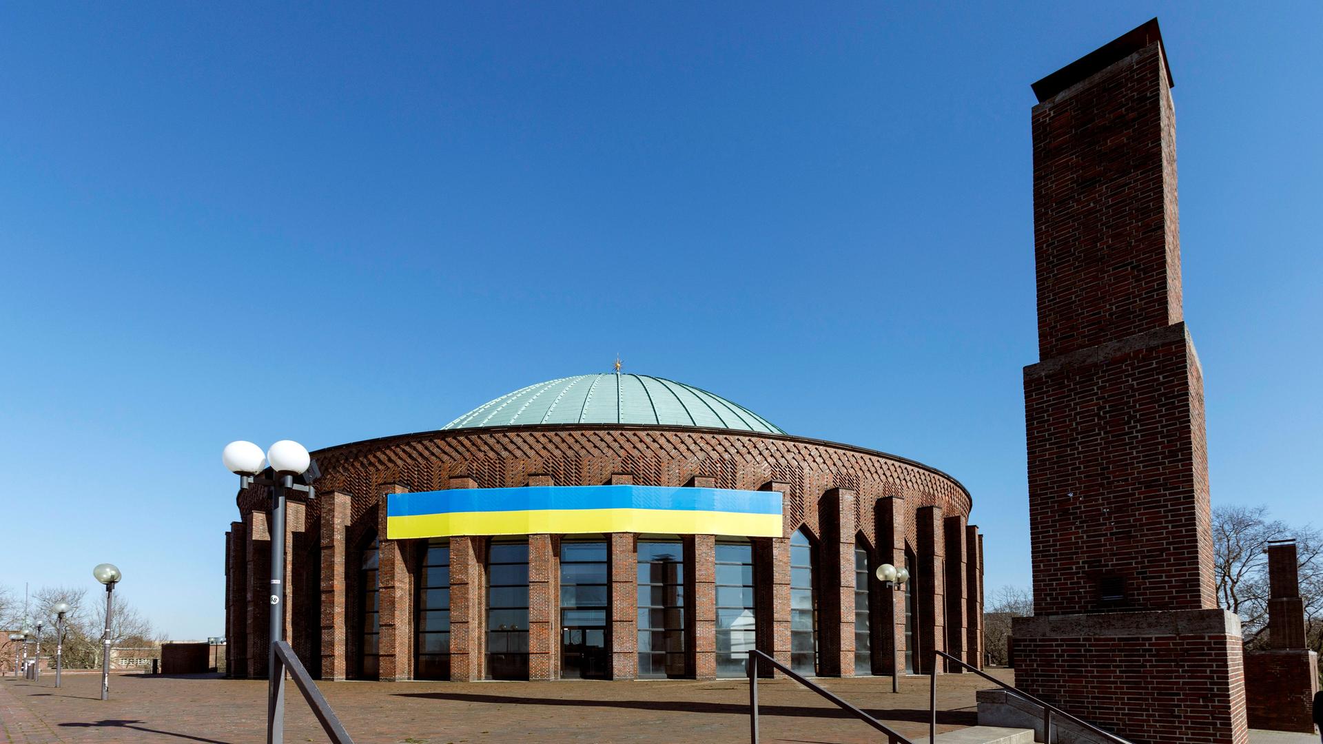 Die blau-gelbe Nationalfahne der Ukraine in an der runden Tonhalle Düsseldorf gespannt und damit weit sichtbar.
